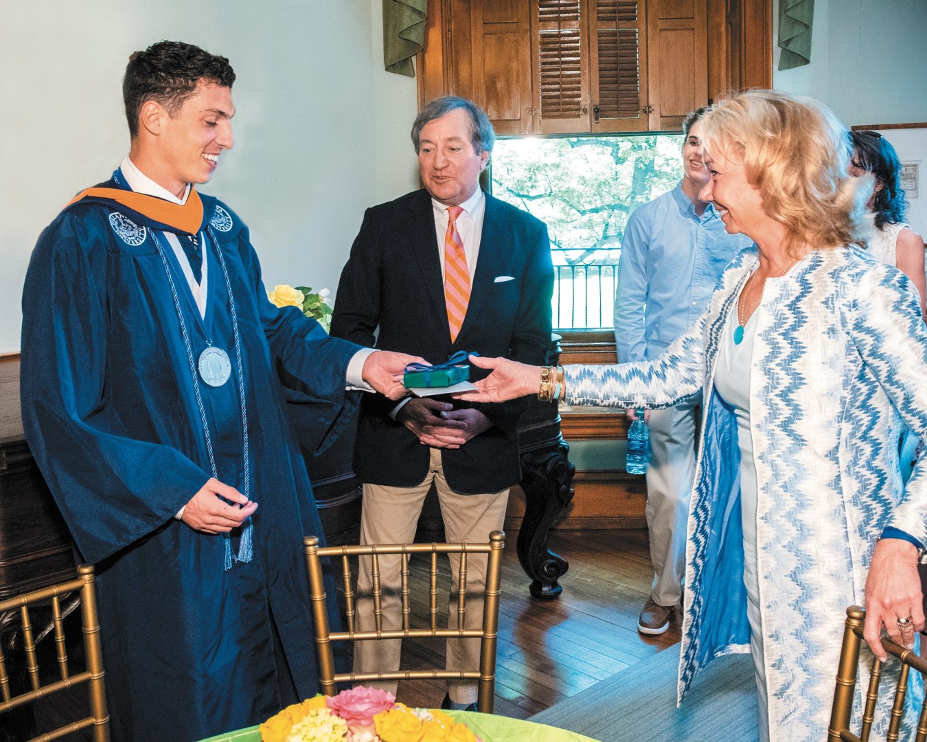 Wearing his regalia, Alex Alberi receives a graduation gift from Polly and Terry O’Toole