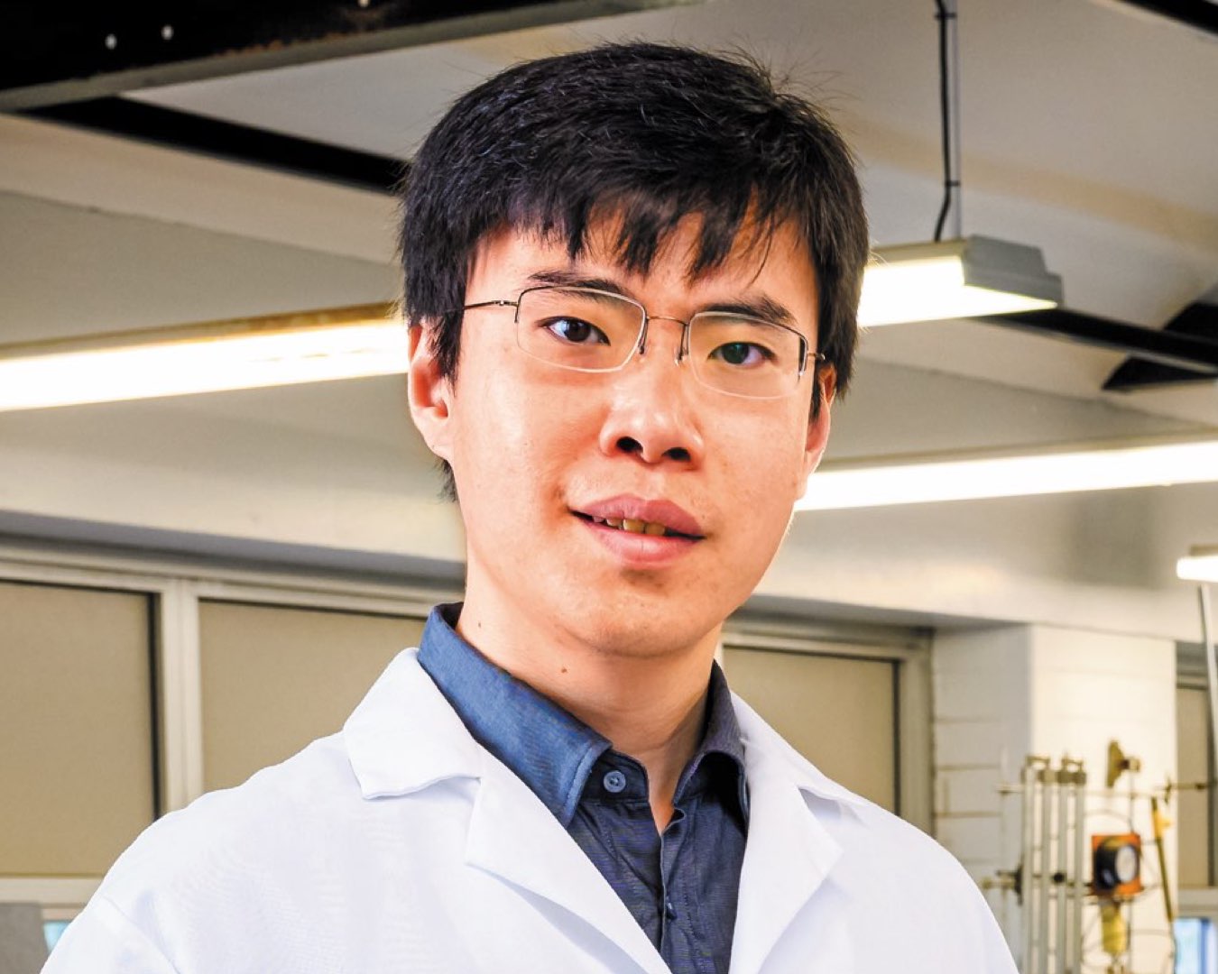 Headshot of PhD student Ji Lang wearing glasses in a white lab coat