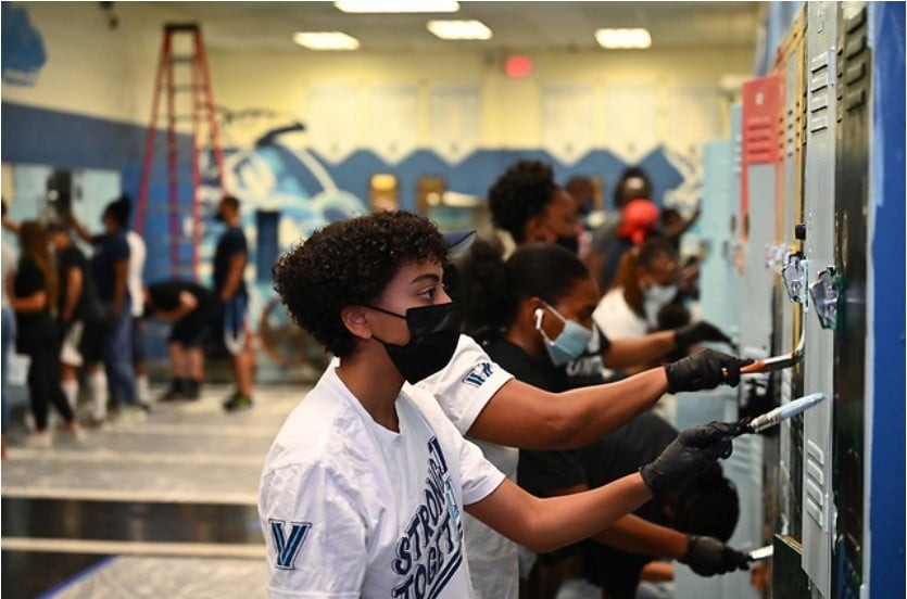 MLK JR Day of Service Alumni and students painting lockers in a school