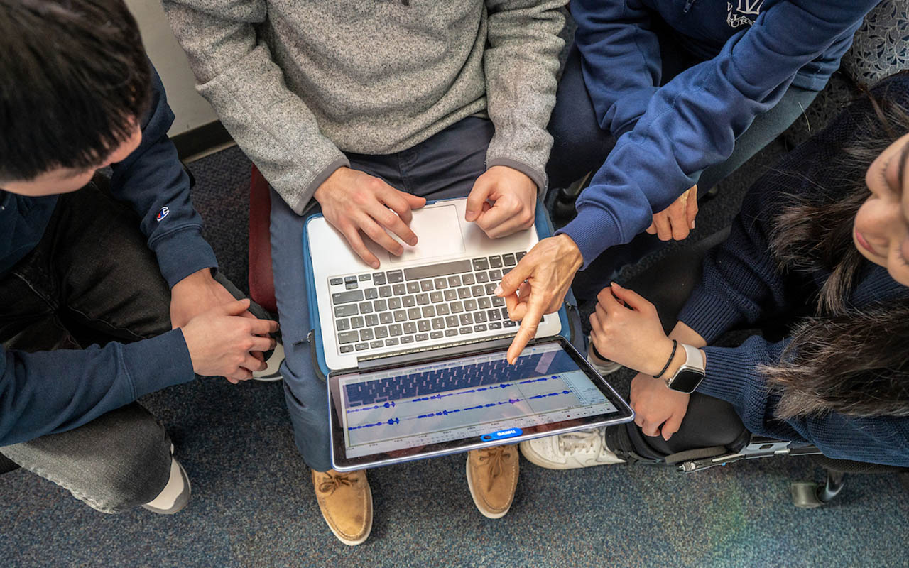 Multiple people viewing a laptop