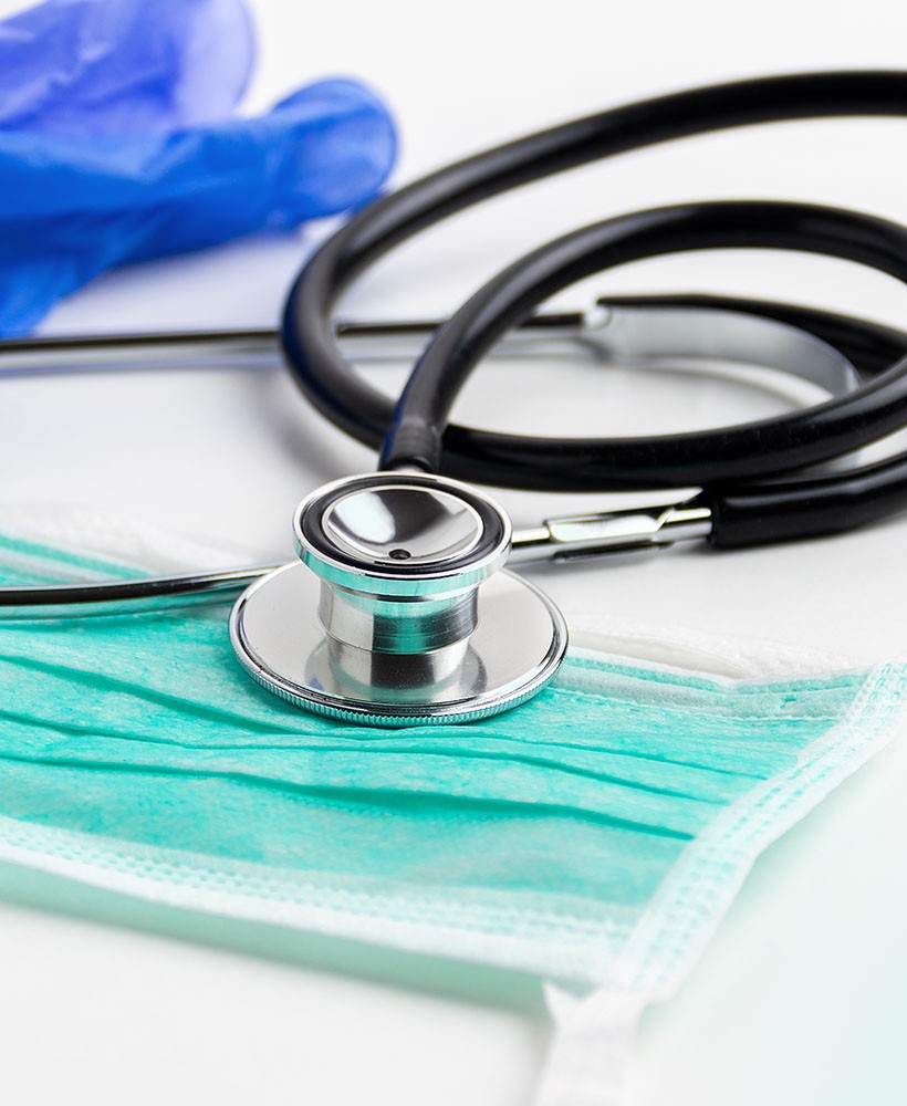 health-center-header Stethescope on a table with a mask and gloves.
