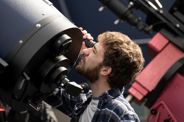 A student looks through a telescope in the observatory.