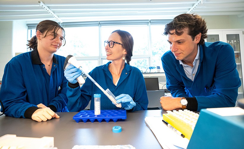 Two students work alongside a professor in a science lab