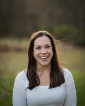 Ashley Mayes Woman with brown hair standing in field smiling