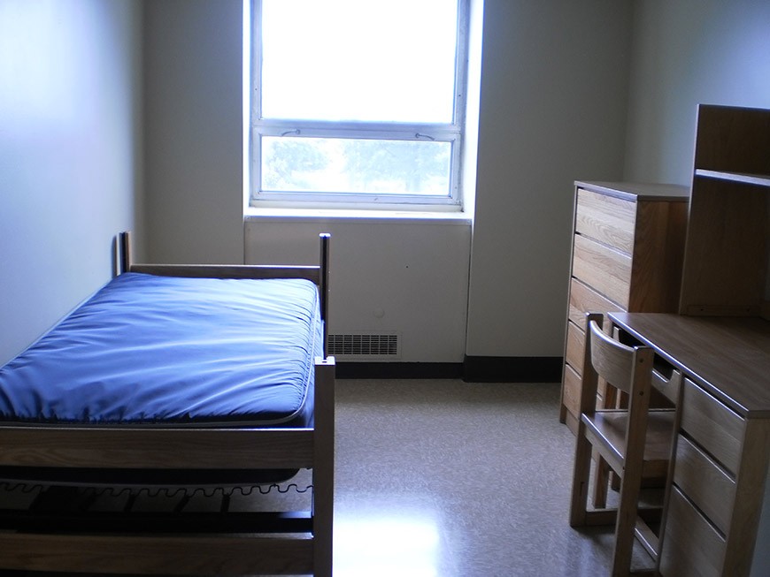 View of a bed, desk and dresser in a St. Mary's Hall single room.