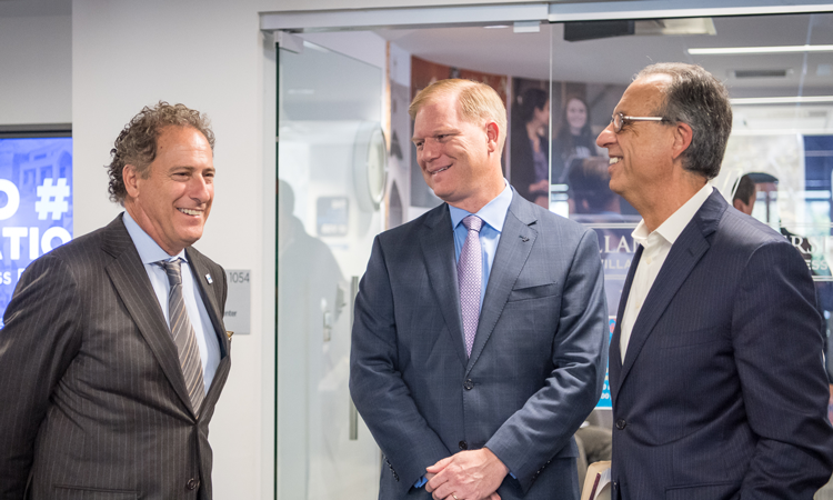 Three men standing and talking while wearing suits
