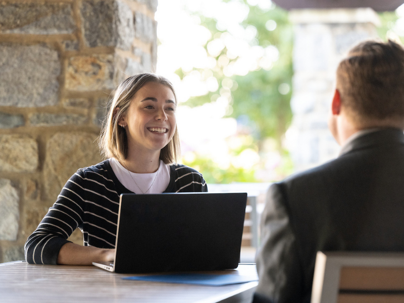 woman with a laptop sitting at a table outside