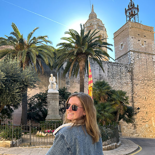 a female student poses in front of palm trees