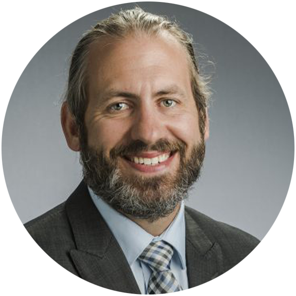 Headshot of Chris Jeffords smiling directly at the camera wearing a suit and tie. 