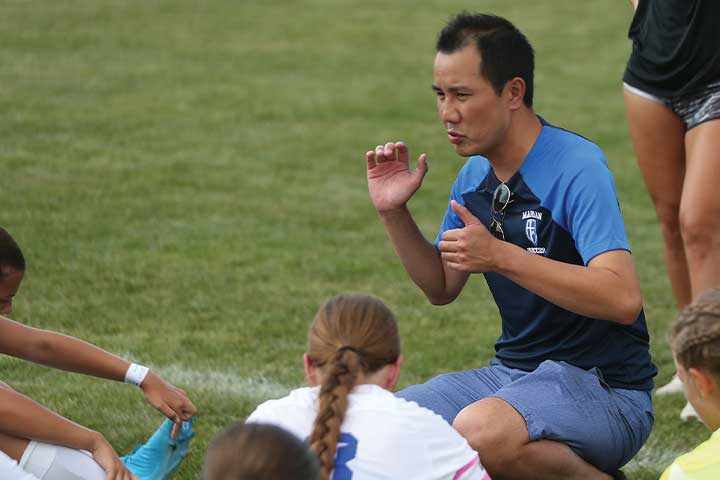 Girls' Soccer Coach Henry Vu huddled with his team on the grassy sidelines.